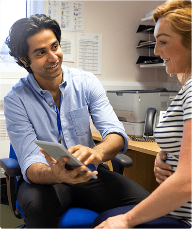 General Practitioner using tablet in consultation with client in black and white striped shirt