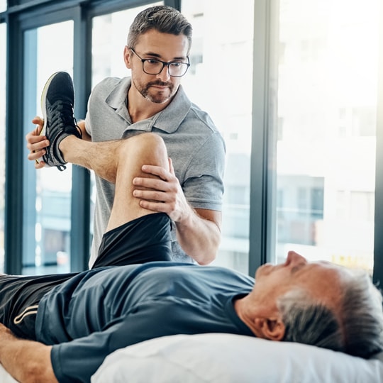 Allied health worker performing physiotherapy on client's left leg