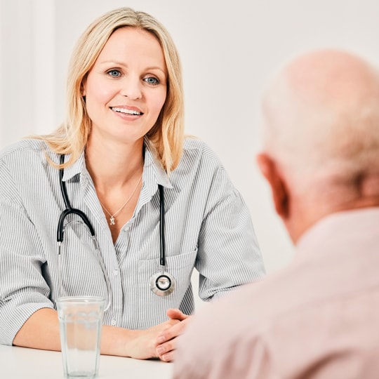 General practitioner with stethoscope around their neck in consultation with senior client